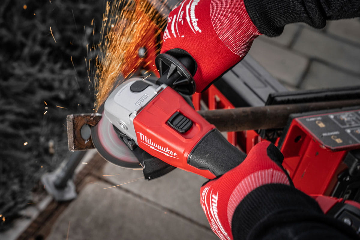 szlifierka Milwaukee M18 125 mm podczas cięcia profilu stalowego na budowie